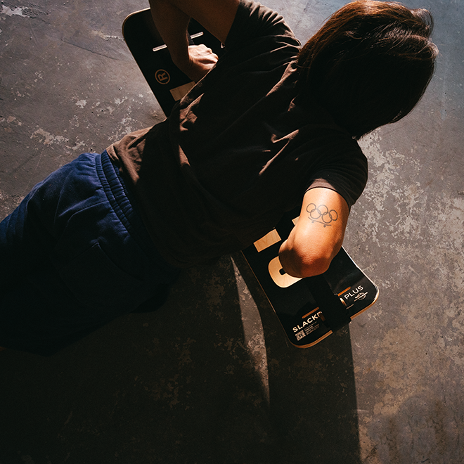 Person with olympic rings tattoo doing a pushup using a caesar slackboard plus