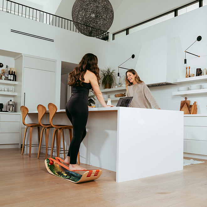 Two women in a modern kitchen with one standing on a GIBBON Dino SlackBoard.